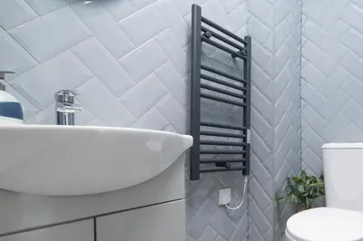 a bathroom with a white sink and a black towel rack at The Foresters Guest House in Inverkip