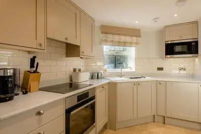 a white kitchen with white cabinets and a sink at Crossbasket Castle, Hotel & Restaurant in High Blantyre