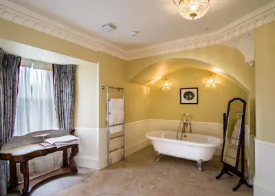 a bathroom with a tub and a window at Crossbasket Castle, Hotel & Restaurant in High Blantyre