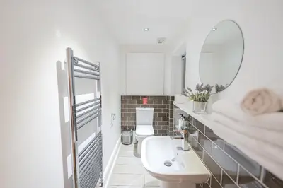 a white bathroom with a sink and a mirror at Edinburgh Castle Apartments in Edinburgh