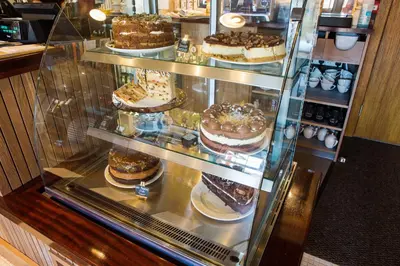 a display case in a bakery with cakes and desserts at Red Squirrel, Stevenston by Marston's Inns in Stevenston