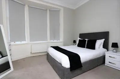 a bedroom with a large bed with white sheets and black pillows at Dreamhouse Apartments Glasgow St Vincent Street in Glasgow