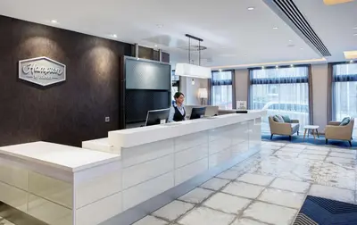 a woman standing at a reception desk in a lobby at Hampton by Hilton Glasgow Central in Glasgow