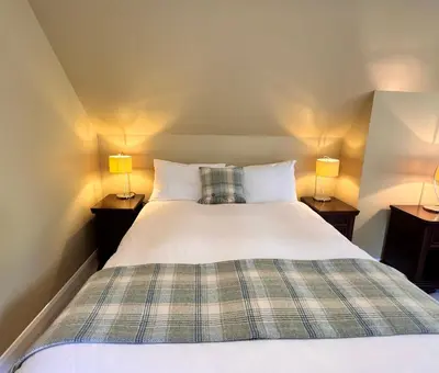 a bedroom with a bed with two lamps on tables at Allt Nan Ros Apartments fort william in Onich