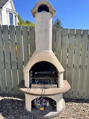 a stone oven sitting in front of a fence at Allt Nan Ros Apartments fort william in Onich