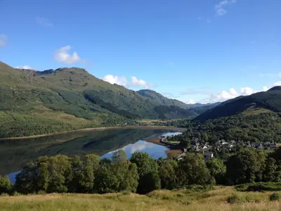 a river in the middle of a valley with mountains at Mansefield House in Arrochar