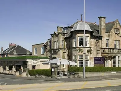 an old building with an umbrella and a restaurant at The Orchard Park Hotel in Giffnock