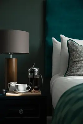 a bed with a table with a lamp and cups on it at The Orchard Park Hotel in Giffnock