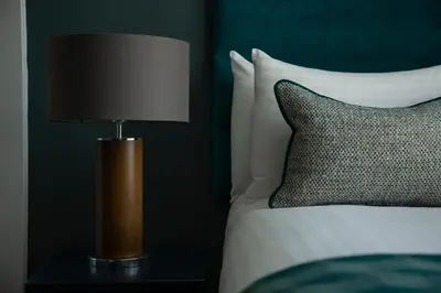 a lamp sitting on a table next to a bed at The Orchard Park Hotel in Giffnock