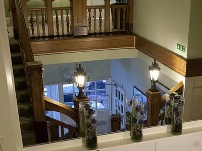 a room with a staircase with lights and flowers in vases at The Orchard Park Hotel in Giffnock