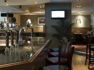 a bar in a restaurant with chairs and a counter at The Orchard Park Hotel in Giffnock