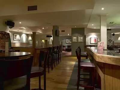a restaurant with a bar and a bunch of chairs at The Orchard Park Hotel in Giffnock