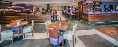a restaurant with tables and chairs and a bar at Parklands Hotel & Country Club in Newton Mearns