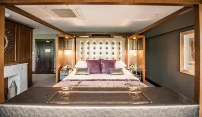 a bedroom with a large bed with purple pillows at Parklands Hotel & Country Club in Newton Mearns