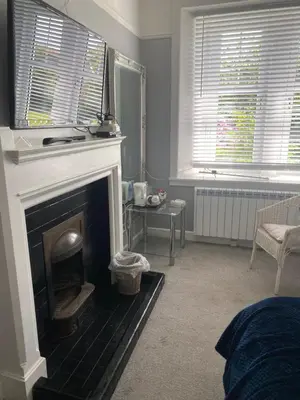 a living room with a fireplace and two windows at Fox House Thirdpart Farm in Beith