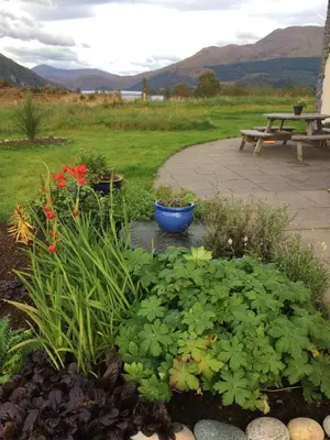 a garden with flowers and plants and a picnic table at Ceo Mara Croft b&b & 2 luxury Cabins in Taynuilt