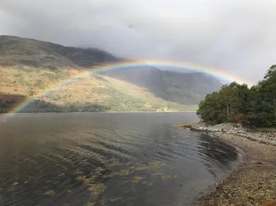 a rainbow over a body of water with a mountain at The Boathouse in Glencoe