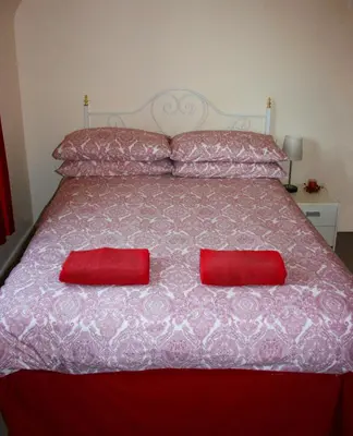 a large bed with two red pillows on it at Park View in Ballachulish