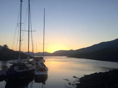 two boats docked in a river at sunset at Park View in Ballachulish