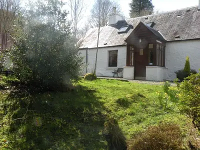 a white house with a bench in a yard at McHugh and Loudon Cottages in Saint Catherines