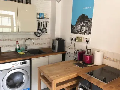 a kitchen with a sink and a washing machine at Castle view&Grassmarket studio flat with Luxury bathroom in Edinburgh