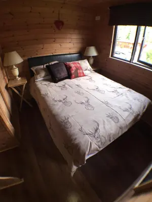 a bed in a log cabin with two lamps on it at Lochlomondlodge22 in Rowardennan