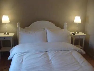 a bed with white sheets and pillows and two lamps at Riggend Farm Accomodation in Airdrie