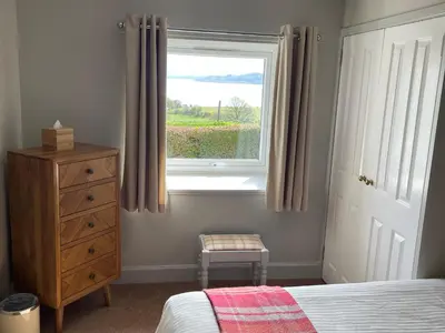 a bedroom with a bed and a window and a dresser at Tigh Grianach in Connel