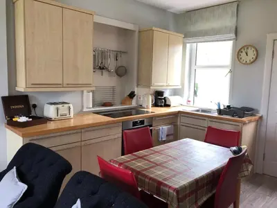 a kitchen with a table and chairs and a kitchen with a sink at Tigh Beg Croft in Lerags