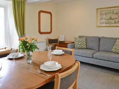 a living room with a wooden table and a couch at Hearthstanes Steading in Polmood