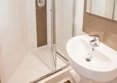 a bathroom with a white sink and a shower at Juniper Court in Stirling