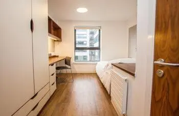 a bedroom with a bed and a desk and a window at Juniper Court in Stirling