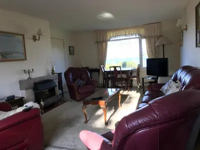 a living room with leather couches and a fireplace at Braeside Craighouse Jura in Craighouse