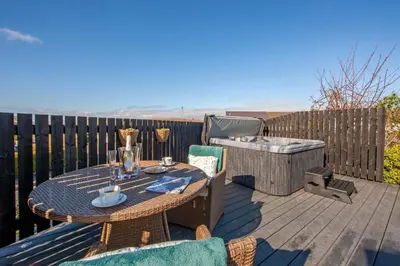 a patio with a table and chairs and a grill at Katie's Flat in Oban