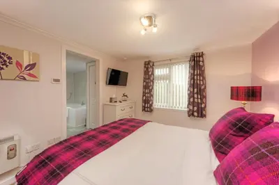 a bedroom with a bed with a plaid blanket at Katie's Flat in Oban