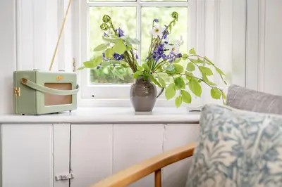 a vase of flowers sitting on a counter with a window at Gardener's Cottage in Crieff