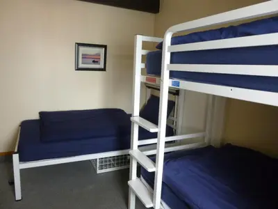 a bedroom with two bunk beds with blue sheets at Port Charlotte Youth Hostel in Port Charlotte