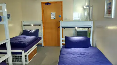 a room with two bunk beds and a door at Port Charlotte Youth Hostel in Port Charlotte