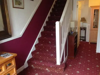 a staircase in a house with a burgundy carpet at Charles's Street in Largs