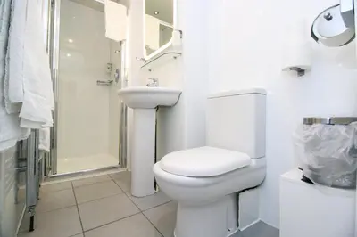 a white bathroom with a toilet and a shower at Kelvingrove Hotel - Sauchiehall St in Glasgow