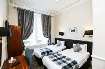 a hotel room with two beds and a table at Kelvingrove Hotel - Sauchiehall St in Glasgow