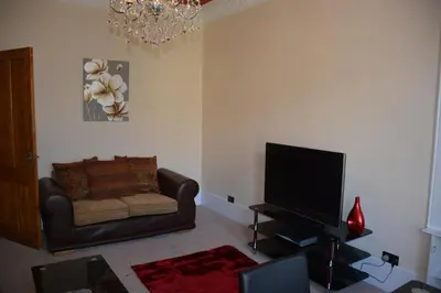 a living room with a couch and a flat screen tv at Townhead Apartments Gallery View in Paisley