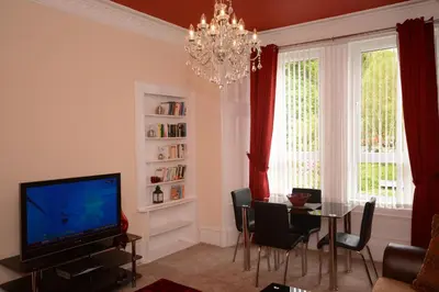 a living room with a television and a dining table at Townhead Apartments Gallery View in Paisley