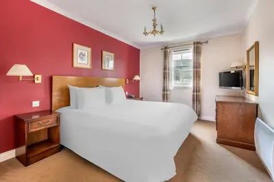 a bedroom with a large white bed and red walls at The Kenmore Club in Kenmore
