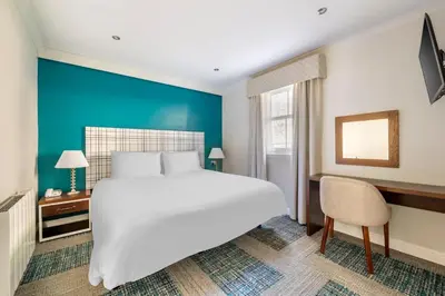 a bedroom with a large white bed and a blue wall at The Kenmore Club in Kenmore