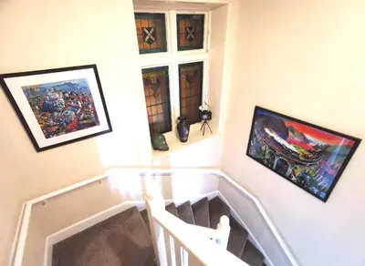 a stairway with paintings on the wall and a window at The Knowe Guest House in Callander