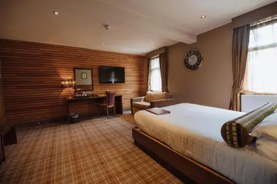 a hotel room with a bed and a desk and a television at Lynnhurst Hotel in Johnstone