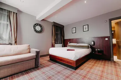a bedroom with a bed and a couch and a clock at Lynnhurst Hotel in Johnstone