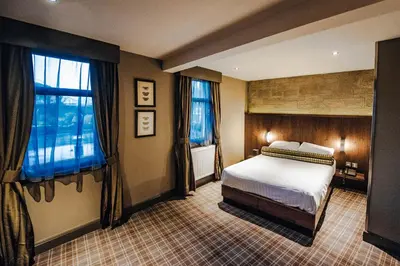 a bedroom with a bed and two windows at Lynnhurst Hotel in Johnstone