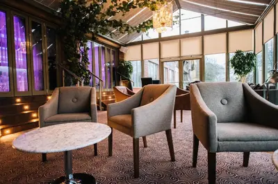 a lobby with chairs and tables and a chandelier at Lynnhurst Hotel in Johnstone